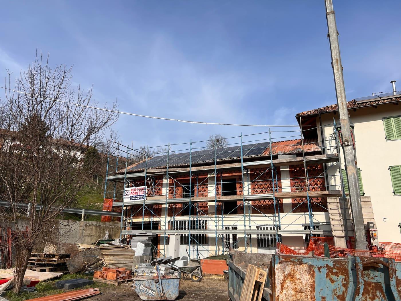 Edificio in ristrutturazione con ponteggi e impianto fotovoltaico già posato sul tetto