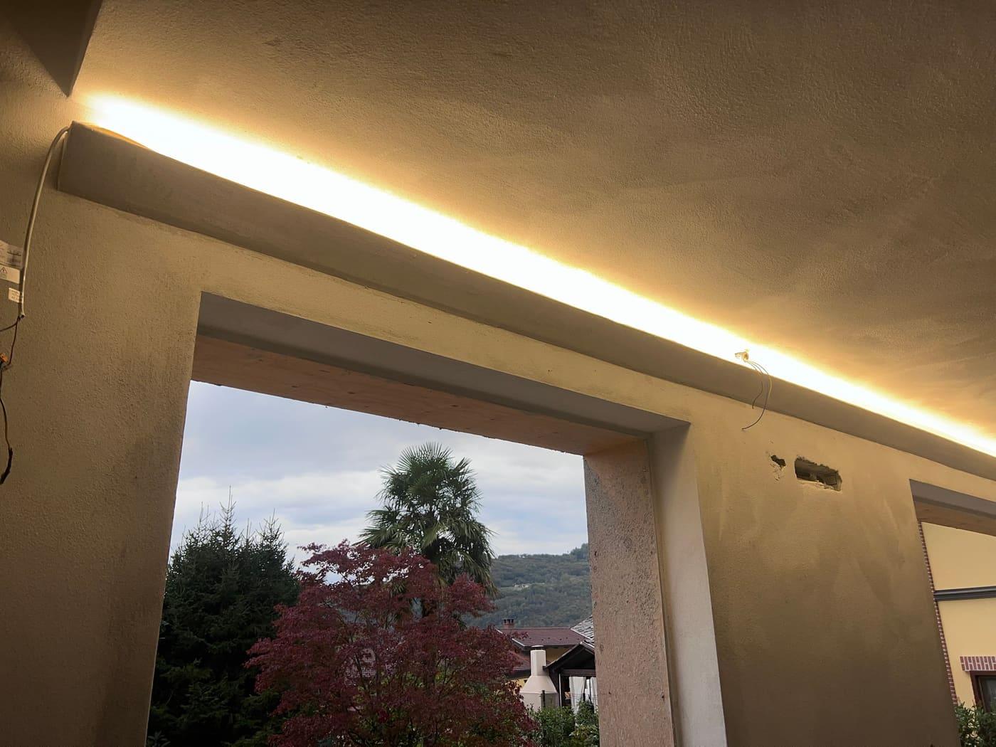 Loggia con linea di luce che corre lungo la trave, affaccio sul giardino