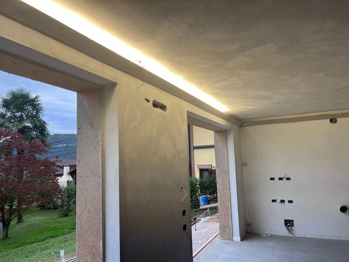 Portico aperto sul giardino con linea luminosa lungo il soffitto