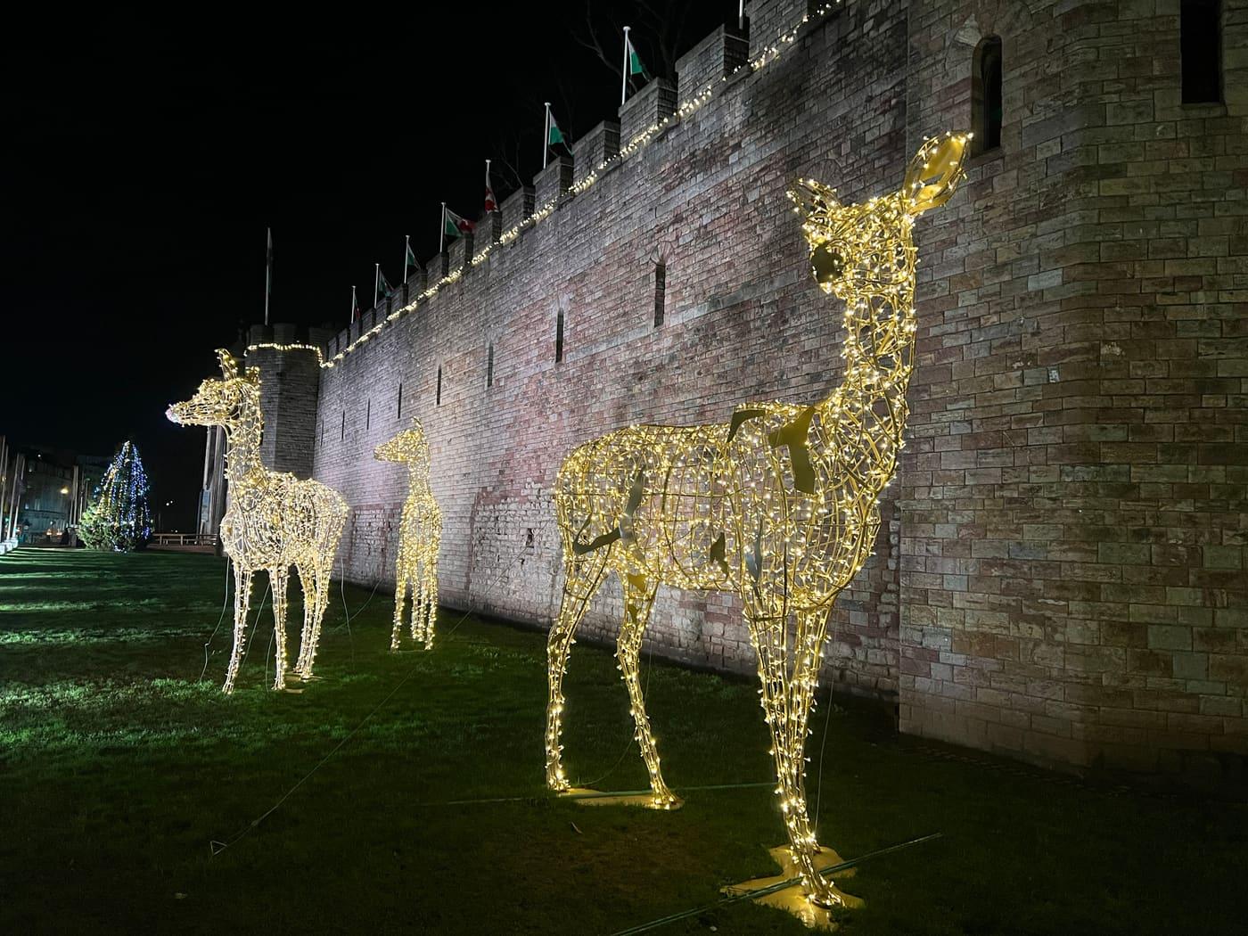 Sagome luminose di cervi ai piedi di mura antiche, di notte