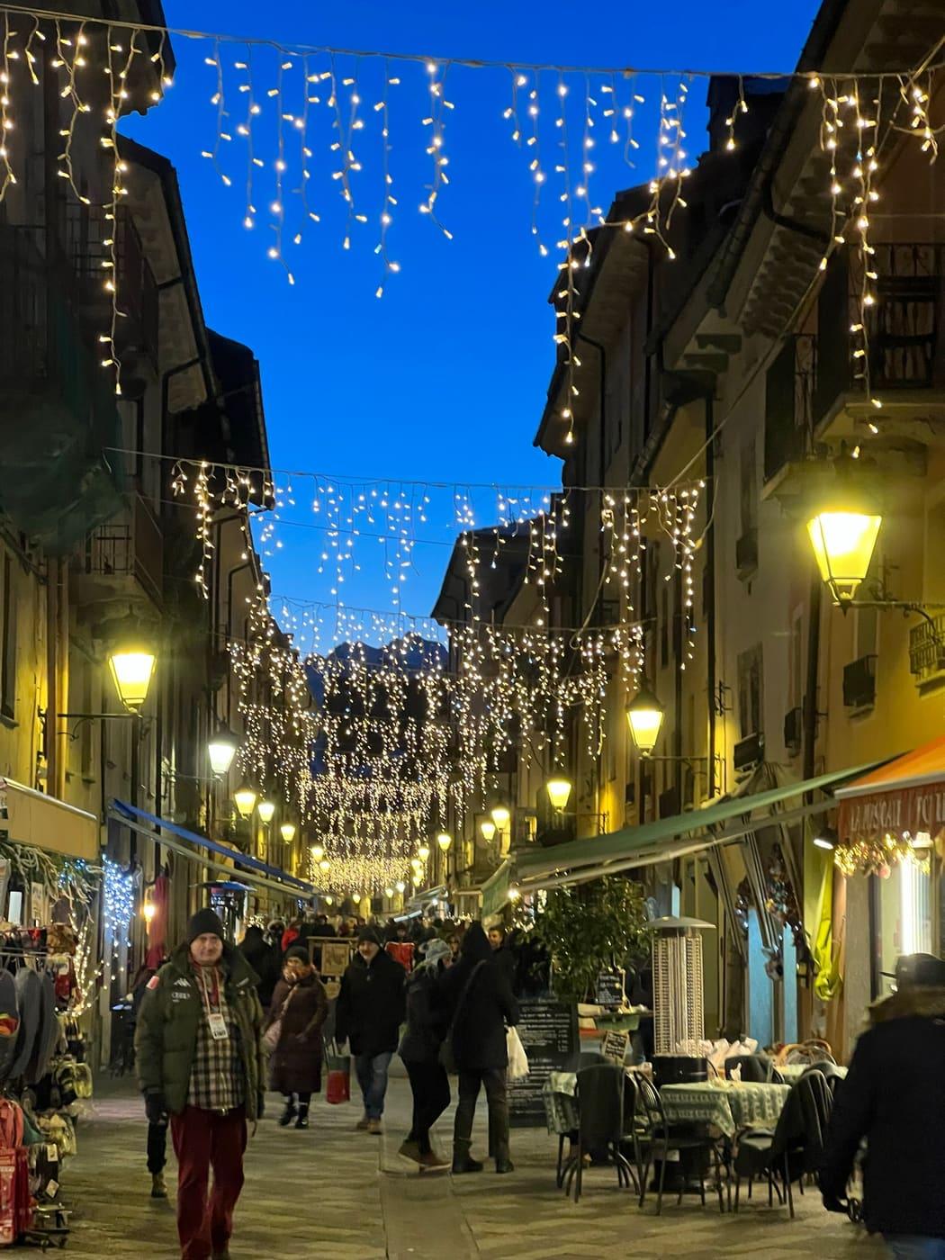 Via del centro con tende di luce sospese fra i palazzi, all'ora blu