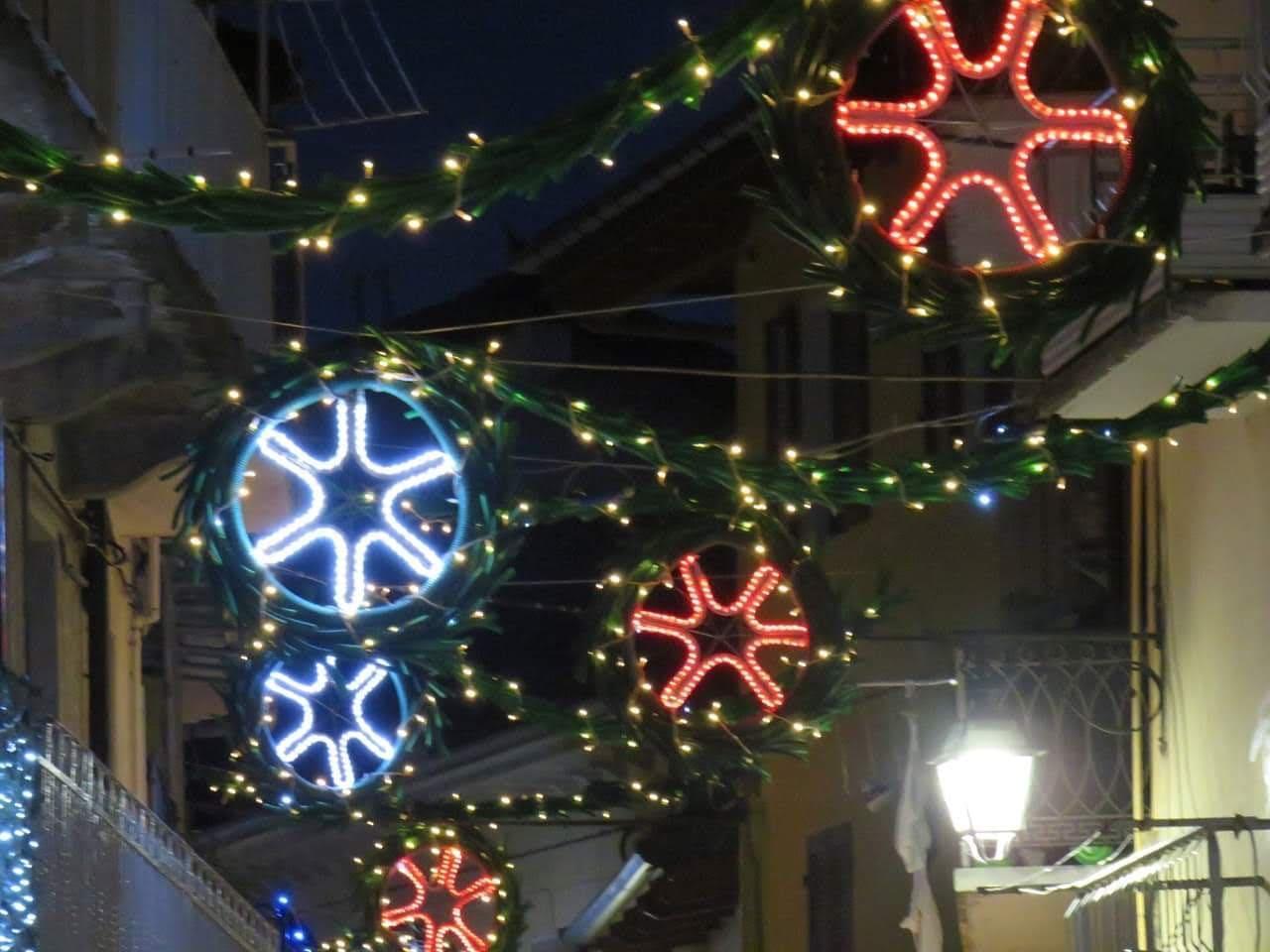 Fiocchi di neve luminosi bianchi e rossi appesi sopra una via