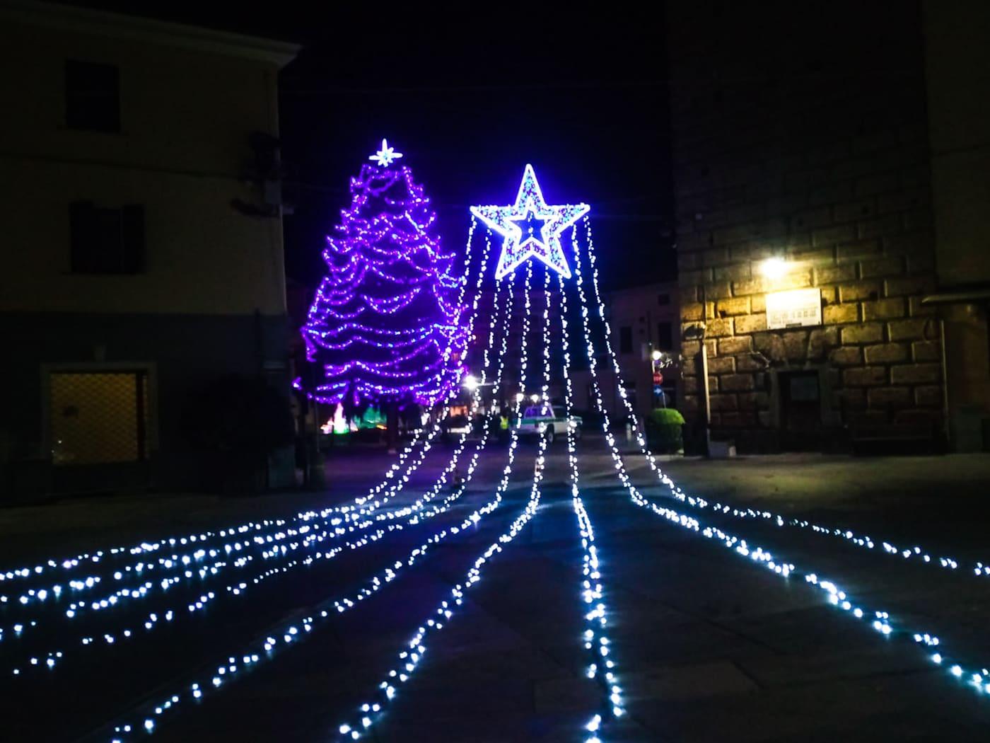 Albero luminoso con code di luce che scendono fino a terra in una piazza